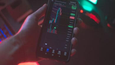 Hand holding smartphone displaying cryptocurrency trading app with financial data.