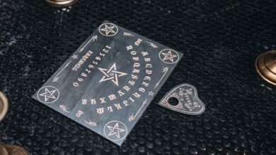 A mystical Ouija board setup with candles on a dark textured surface.