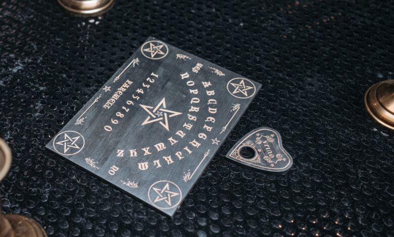 A mystical Ouija board setup with candles on a dark textured surface.