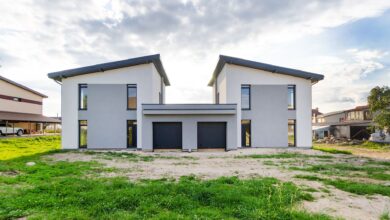 Front view of twin modern houses with a symmetrical architectural design under a cloudy sky.