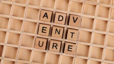 Wooden blocks arranged to spell 'Adventure' on a grid background.