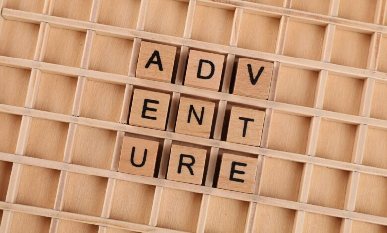 Wooden blocks arranged to spell 'Adventure' on a grid background.
