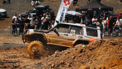 A thrilling moment in an off-road car race with spectators and flying mud, capturing the intensity and excitement.