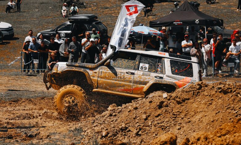 A thrilling moment in an off-road car race with spectators and flying mud, capturing the intensity and excitement.