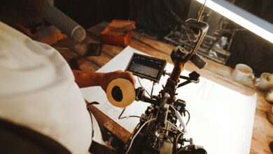A filmmaking professional adjusting camera equipment on a wooden desk in a studio setting.