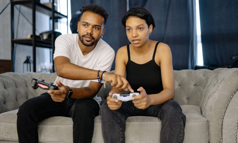 Two young adults enjoying video gaming together on a cozy couch at home.