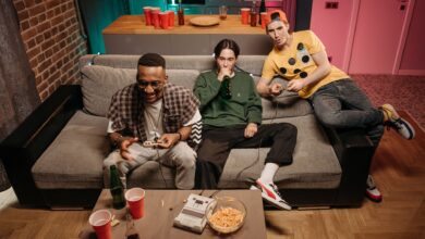 Three friends having fun gaming and drinking beer in a cozy indoor setting.