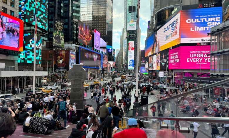 Dynamic scene in Times Square, New York City with colorful billboards and diverse crowd.