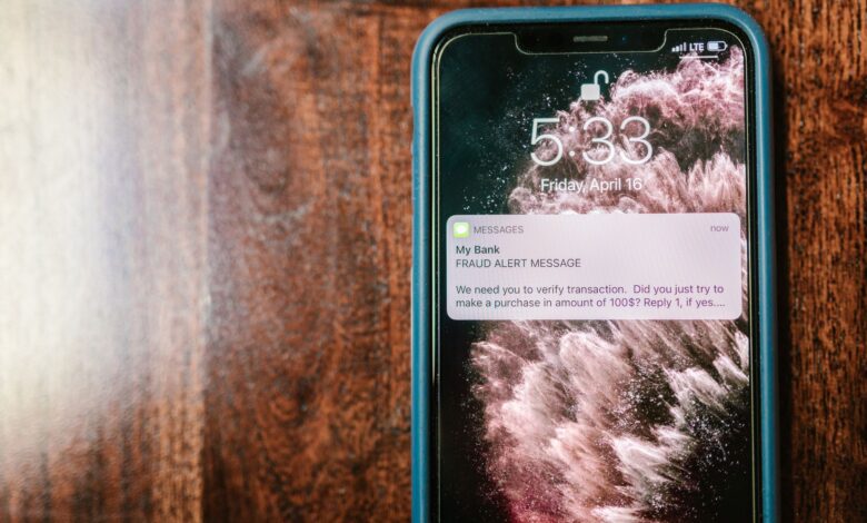 Close-up of a smartphone displaying a fraud alert notification on a wooden surface.