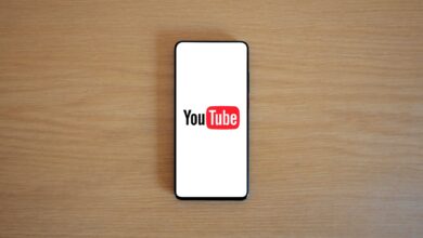 Top view of smartphone displaying YouTube logo on a wooden surface, showcasing modern technology.