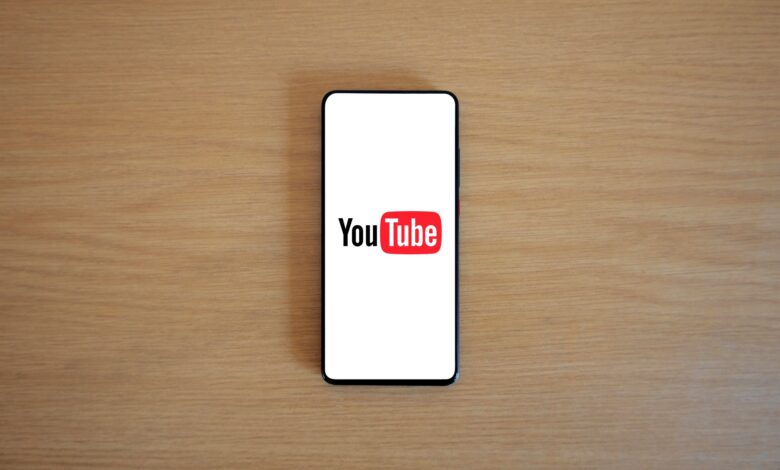 Top view of smartphone displaying YouTube logo on a wooden surface, showcasing modern technology.
