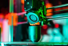 Close-up of a 3D printer creating a product in neon lighting.