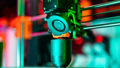 Close-up of a 3D printer creating a product in neon lighting.