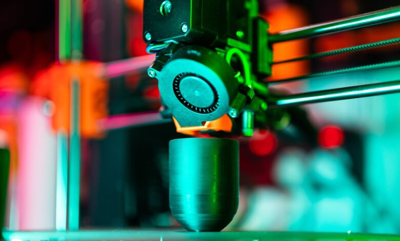 Close-up of a 3D printer creating a product in neon lighting.