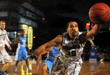 Intense basketball game with athletes in action on an outdoor court during nighttime.
