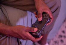 Hands gripping a game controller, engaged in a video game indoors.