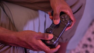 Hands gripping a game controller, engaged in a video game indoors.