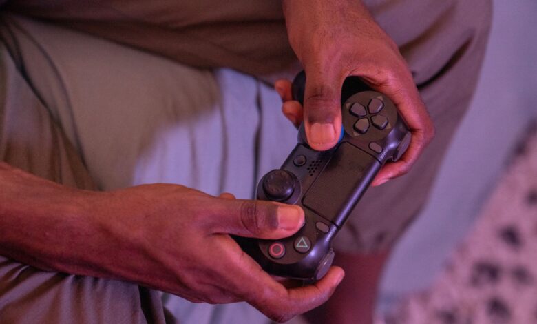 Hands gripping a game controller, engaged in a video game indoors.