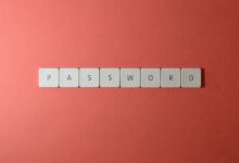Focus on password security with white keyboard tiles spelling 'PASSWORD' on a coral background.