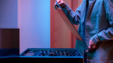 A man carefully fits a glass panel onto a gaming PC while adjusting internal cables.