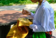 Vietnamese woman engaging in traditional embroidery outdoors in Hue, Vietnam.