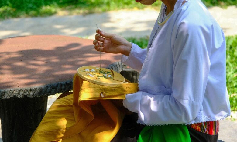 Vietnamese woman engaging in traditional embroidery outdoors in Hue, Vietnam.