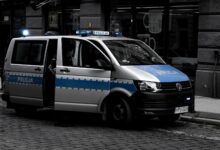 A police van parked on a cobblestone street in an urban setting.