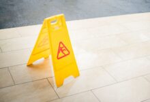 A bright yellow caution sign placed on a tile floor indicating a wet area for safety.