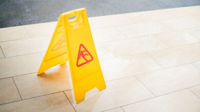 A bright yellow caution sign placed on a tile floor indicating a wet area for safety.