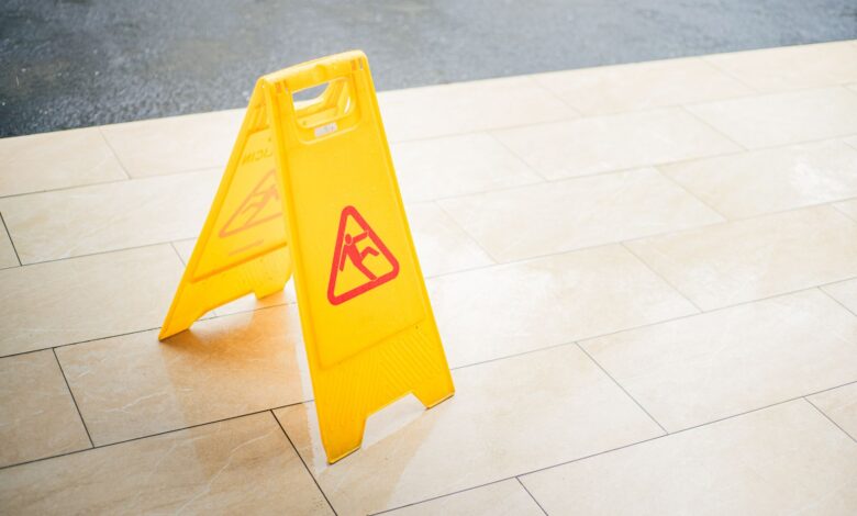 A bright yellow caution sign placed on a tile floor indicating a wet area for safety.