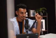 Confident young man speaking into a microphone during a podcast recording in a modern studio.