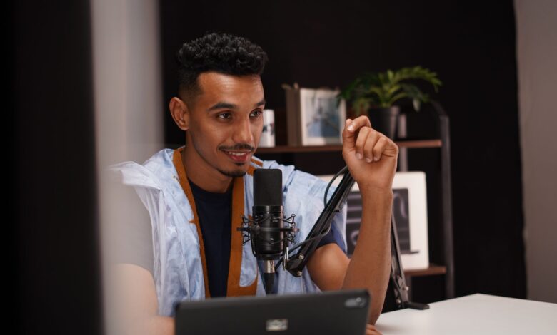 Confident young man speaking into a microphone during a podcast recording in a modern studio.