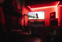 Sleek gaming setup featuring a microphone, neon lights, and a gaming chair in a home studio.