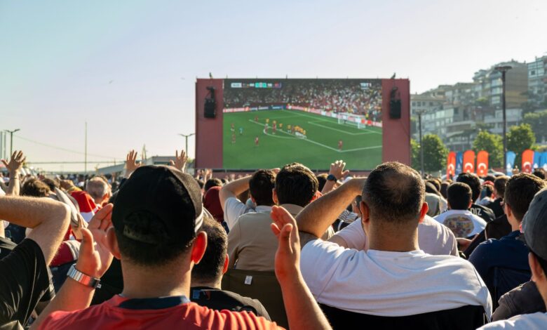 Crowd watching a soccer game on a large screen outdoors in Istanbul, Türkiye.