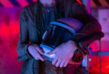 A person holding an astronaut helmet with neon lighting in a sci-fi setting.