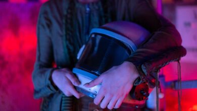 A person holding an astronaut helmet with neon lighting in a sci-fi setting.