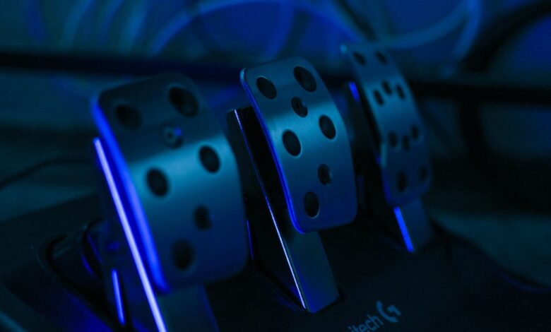 Detailed shot of gaming pedals illuminated by blue light, perfect for racing simulation setups.