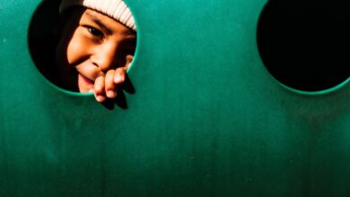 A joyful child peeping through a hole in a playground structure, playfully smiling.