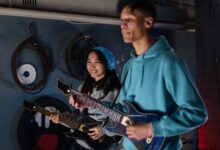 Two friends playing an interactive guitar video game indoors, showcasing joy and teamwork.