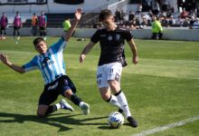 Two football players competing fiercely during a match, creating dramatic sports action.