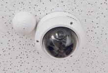 Close-up of a round dome surveillance camera installed on a speckled ceiling for security monitoring.