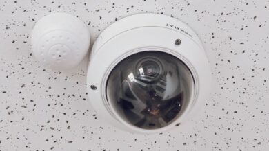 Close-up of a round dome surveillance camera installed on a speckled ceiling for security monitoring.