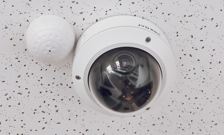 Close-up of a round dome surveillance camera installed on a speckled ceiling for security monitoring.