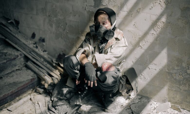 A young person in a gas mask sits in a decaying, abandoned building, evoking themes of survival and desolation.