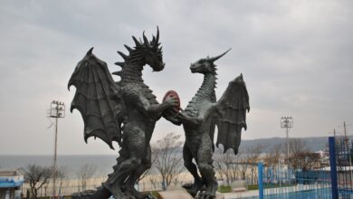 Two majestic dragon statues facing each other by the seaside.