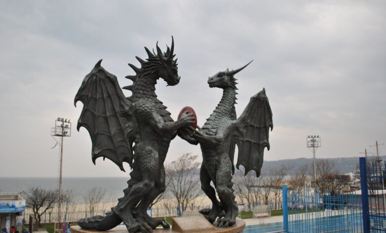 Two majestic dragon statues facing each other by the seaside.