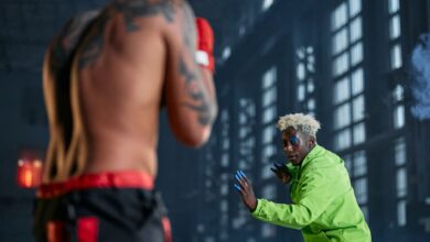 Intense indoor cosplay martial arts duel between two men in vibrant outfits.