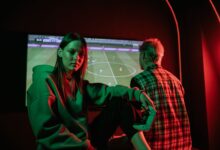 Two young adults playing video games intensely indoors with gaming controllers.