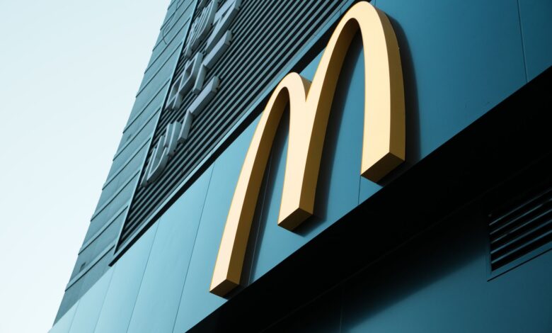Large fast food restaurant golden arch sign on a modern building facade.
