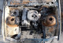 Aerial view of a burnt-out engine in an abandoned car, showcasing rust and decay.